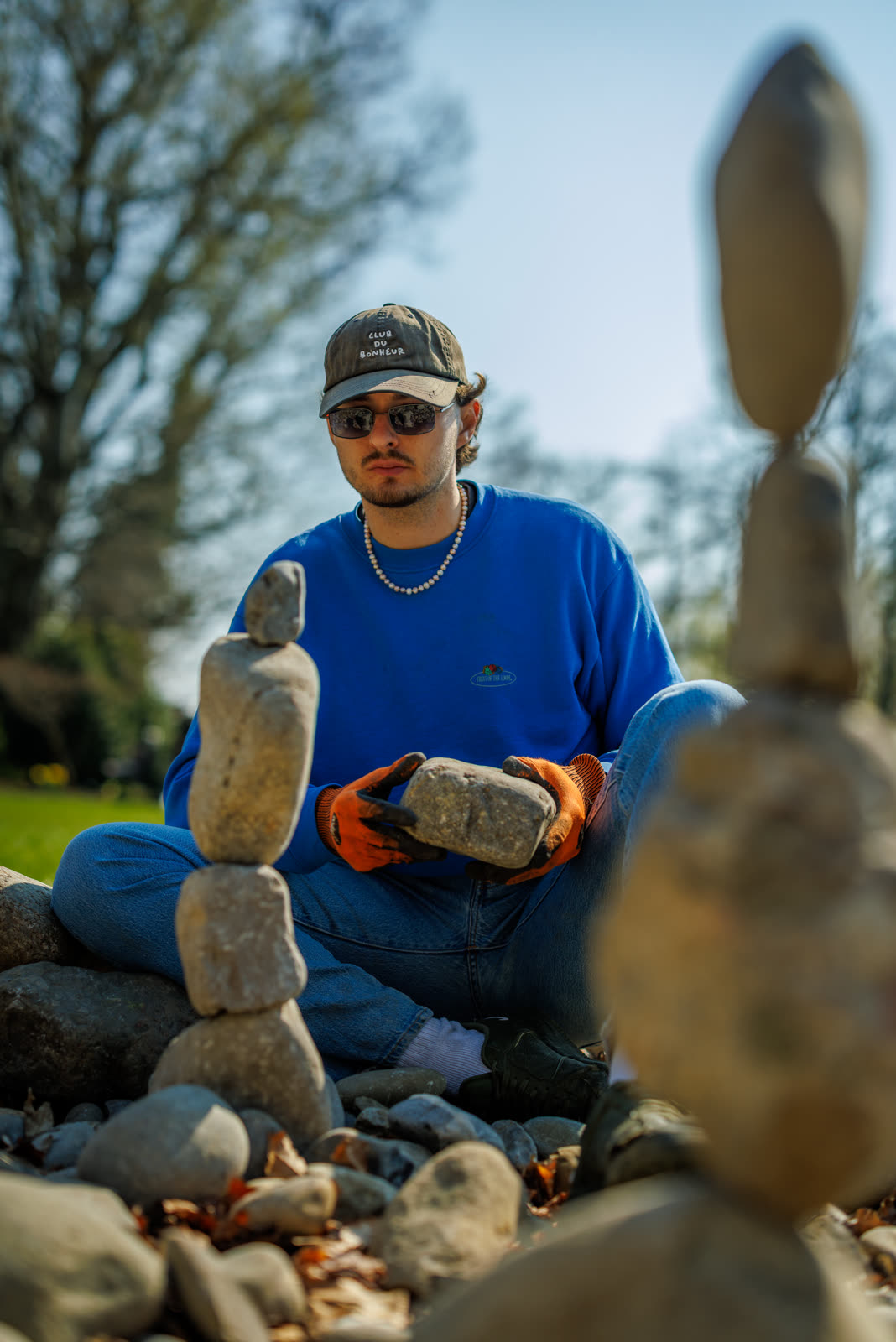 A workshop participant holding a stone among their finished balanced stacks