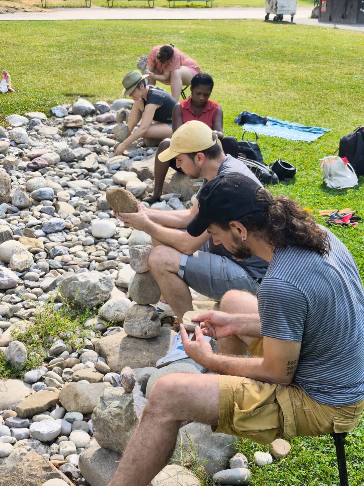 Workshop group building stone stacks along the pebble bed in a Zürich park